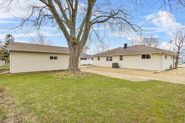 rear view of house featuring driveway, central AC unit, and a lawn