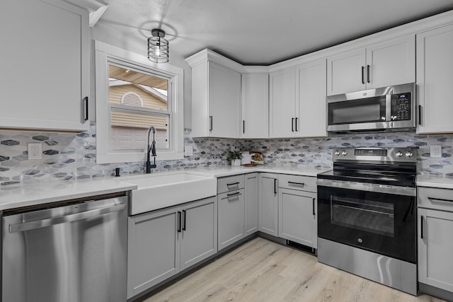 kitchen featuring light countertops, appliances with stainless steel finishes, decorative backsplash, and a sink