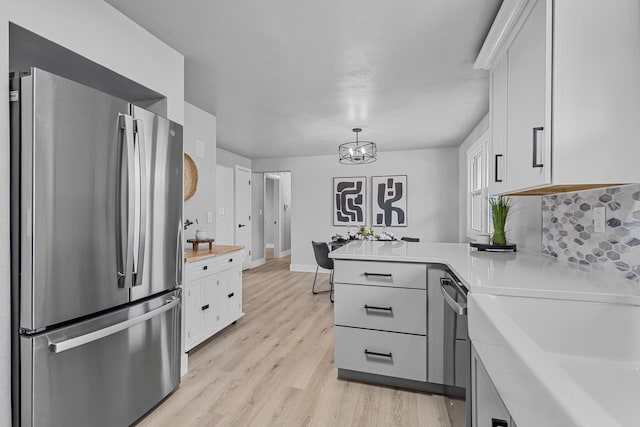 kitchen featuring light countertops, a peninsula, appliances with stainless steel finishes, and white cabinets