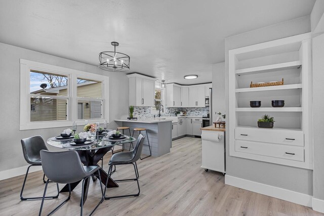 dining room featuring light wood finished floors, baseboards, and a chandelier