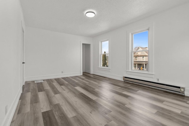76 E Johnson St, Fond Du Lac, WI 54935 - unfurnished room with wood finished floors, visible vents, baseboards, a textured ceiling, and baseboard heating