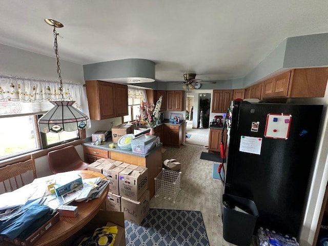 kitchen with brown cabinetry, ceiling fan, a peninsula, and freestanding refrigerator