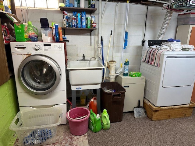 washroom with concrete block wall, a sink, independent washer and dryer, and laundry area