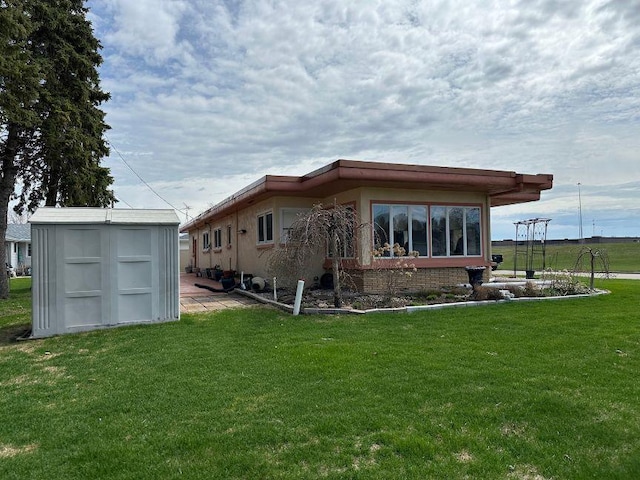 back of house with an outdoor structure, a yard, and a storage unit
