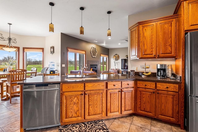 kitchen with stainless steel appliances, a sink, brown cabinets, and hanging light fixtures