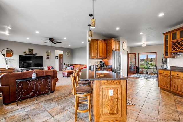 kitchen with recessed lighting, a kitchen breakfast bar, a sink, freestanding refrigerator, and open floor plan