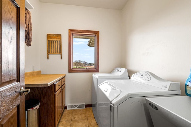 laundry area featuring baseboards, visible vents, independent washer and dryer, cabinet space, and light tile patterned floors