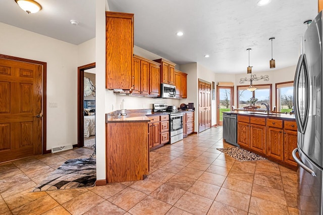 kitchen with stainless steel appliances, a sink, dark countertops, visible vents, and brown cabinetry