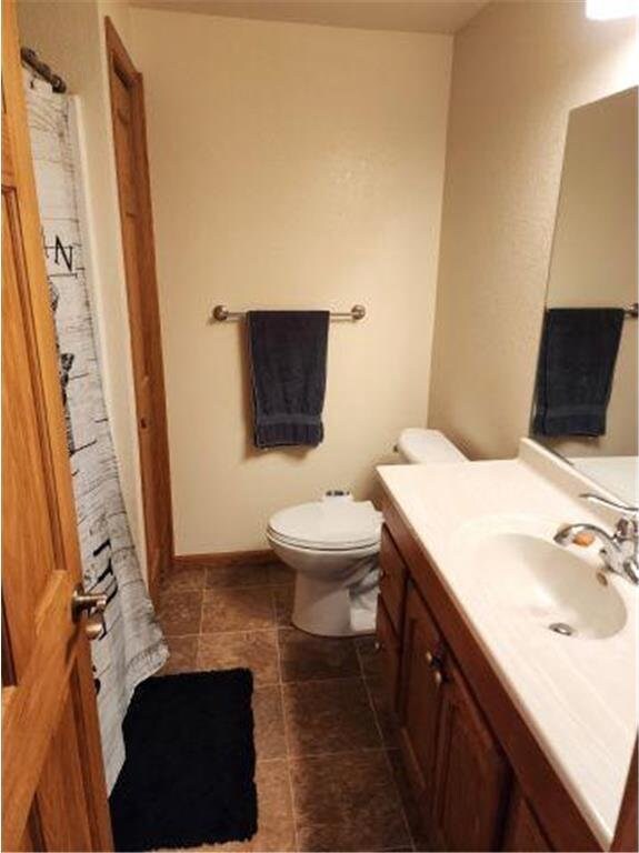 21 N Main St, Luck, WI 54853 - full bathroom featuring tile patterned flooring, toilet, vanity, a shower with curtain, and baseboards