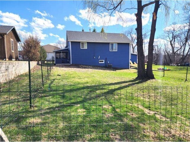 21 N Main St, Luck, WI 54853 - rear view of property with fence, a sunroom, and a yard