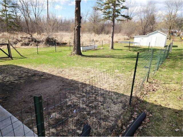 21 N Main St, Luck, WI 54853 - view of yard with an outdoor structure, fence, and a storage unit