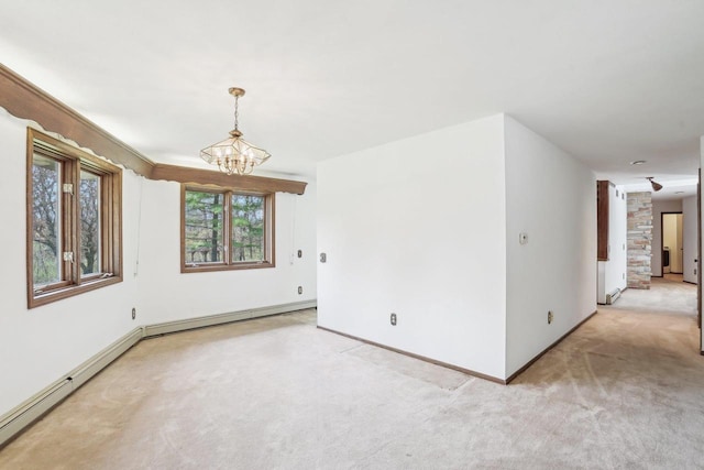 spare room with baseboards, a notable chandelier, and light colored carpet