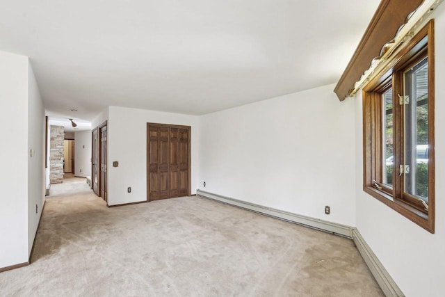 empty room featuring baseboards, a baseboard radiator, and light colored carpet