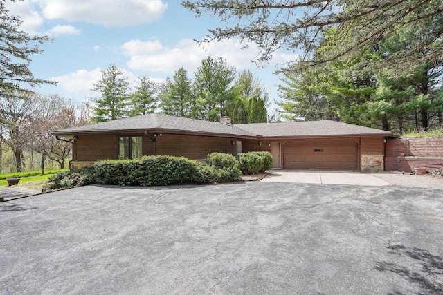 view of front facade featuring an attached garage, driveway, and a chimney