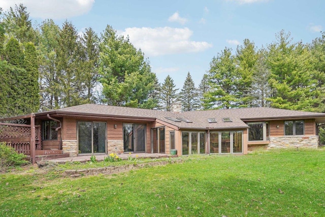 back of property featuring a yard and stone siding