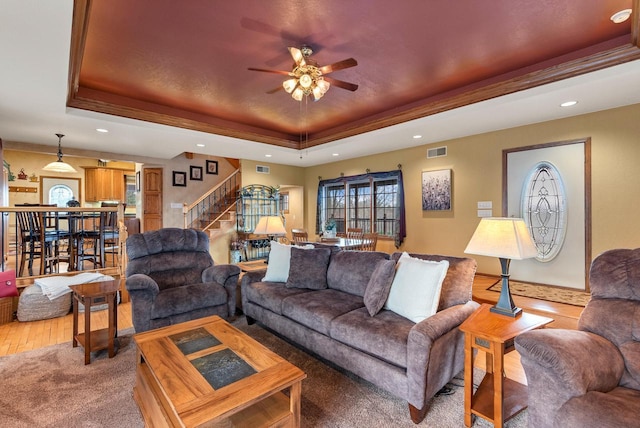 living area featuring a tray ceiling, stairway, a ceiling fan, and recessed lighting