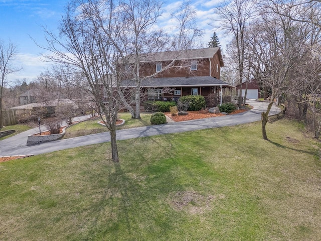 view of front of home with aphalt driveway, a front lawn, an outbuilding, a porch, and roof with shingles