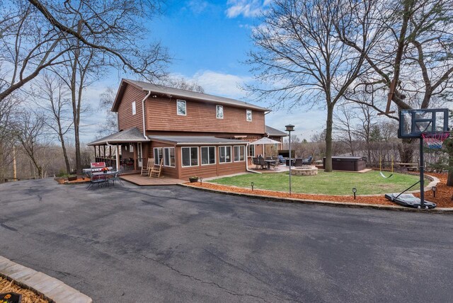 back of house with a gazebo, a lawn, an outdoor fire pit, a patio, and a sunroom