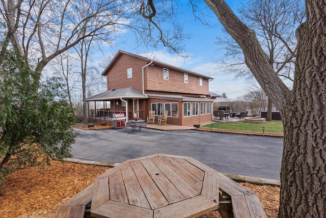 rear view of house featuring outdoor dining space, a patio, and an outdoor fire pit