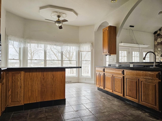 1835 N Davies Dr, Summit, WI 53066 - kitchen with dark countertops, brown cabinetry, ceiling fan, and a sink