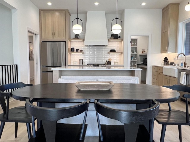 3156 Breeze Dr, Sun Prairie, WI 53590 - kitchen with a sink, freestanding refrigerator, a center island, tasteful backsplash, and custom exhaust hood