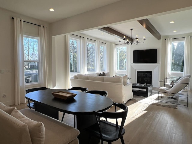 3156 Breeze Dr, Sun Prairie, WI 53590 - dining area featuring wood finished floors, a glass covered fireplace, a chandelier, beam ceiling, and recessed lighting