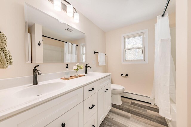 W2252 Spring Lake Rd, Markesan, WI 53946 - bathroom with a baseboard radiator, toilet, wood finished floors, and a sink
