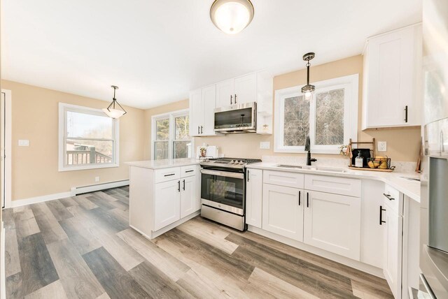 W2252 Spring Lake Rd, Markesan, WI 53946 - kitchen with a peninsula, a sink, light wood-type flooring, baseboard heating, and appliances with stainless steel finishes