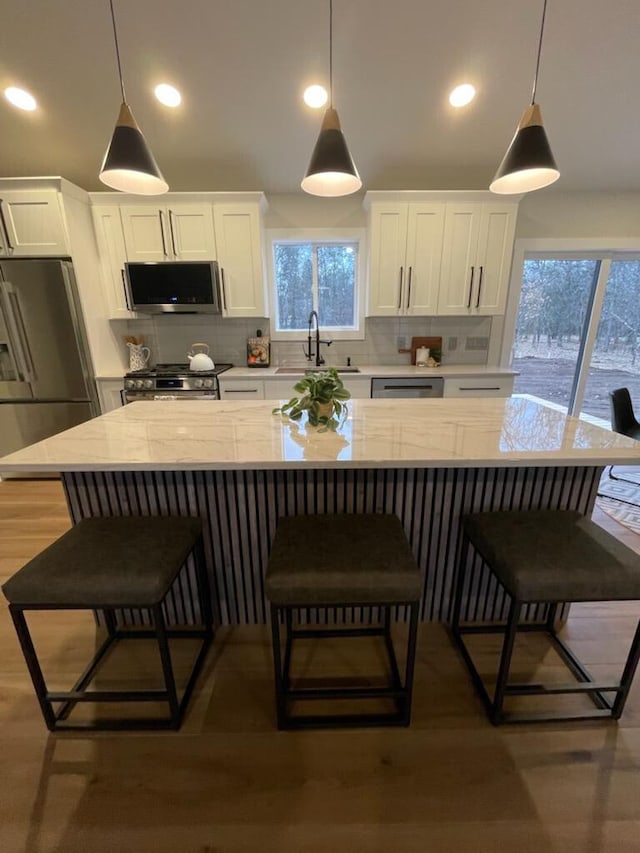 365 13th Dr, Nekoosa, WI 54457 - kitchen featuring stainless steel appliances, a sink, white cabinets, decorative backsplash, and a breakfast bar