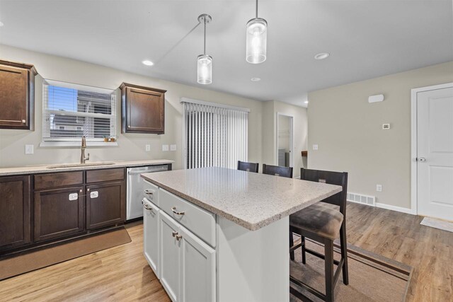 5872 Tranquility Trl, Madison, WI 53718 - kitchen featuring a breakfast bar, dishwasher, a sink, pendant lighting, and light wood-style flooring