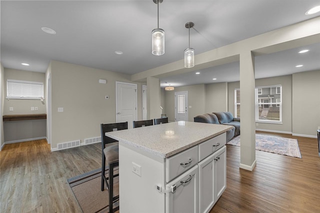 5872 Tranquility Trl, Madison, WI 53718 - kitchen featuring a center island, wood finished floors, a breakfast bar, baseboards, and visible vents