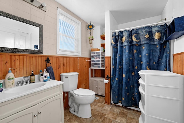 bathroom featuring wood walls, vanity, curtained shower, a wainscoted wall, and toilet