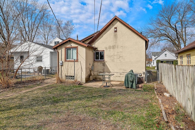 rear view of property with a fenced backyard, a yard, and stucco siding
