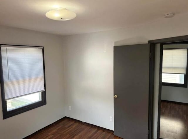 unfurnished room featuring plenty of natural light and dark wood-type flooring