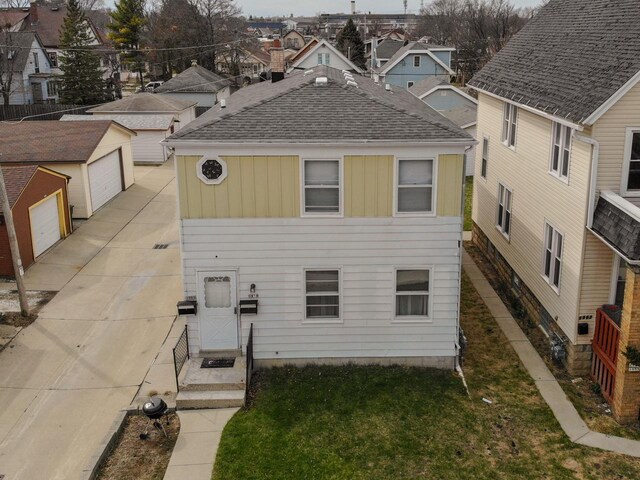 view of front of house featuring a garage, a shingled roof, a front yard, and board and batten siding