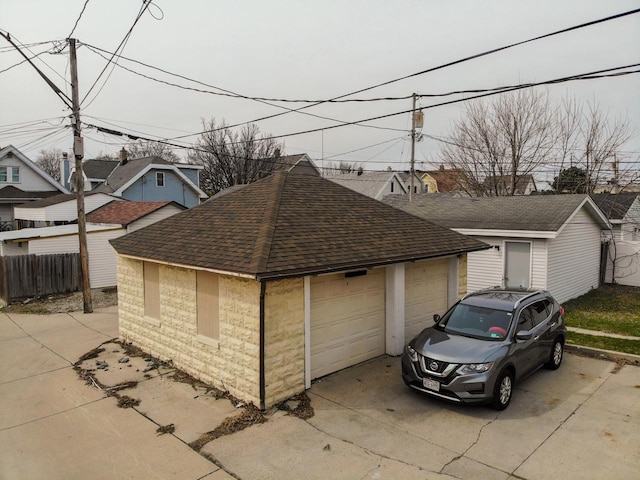 view of front of home with fence, an outdoor structure, roof with shingles, and a garage