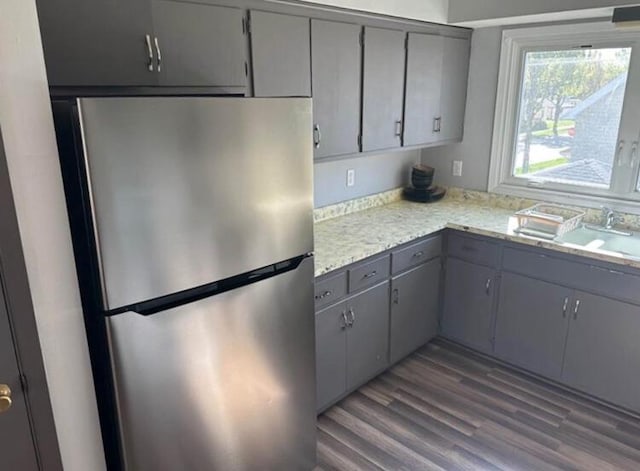 kitchen with gray cabinetry, a sink, light countertops, and freestanding refrigerator