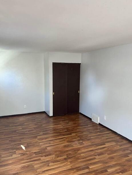 empty room featuring baseboards, wood finished floors, and visible vents