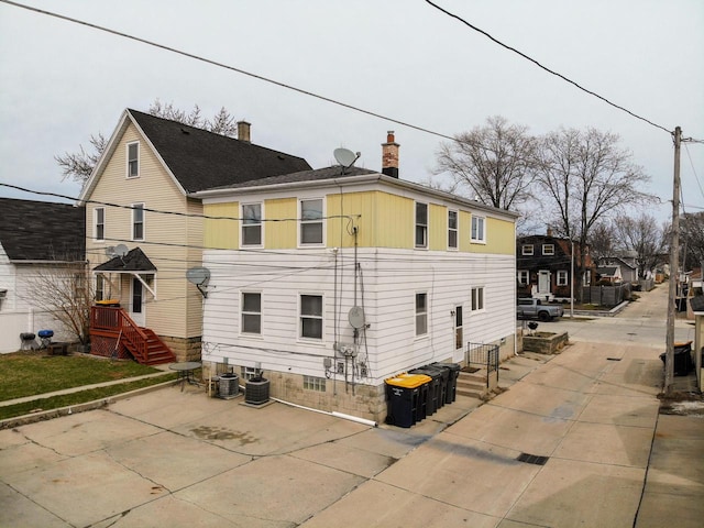 exterior space with a chimney and cooling unit