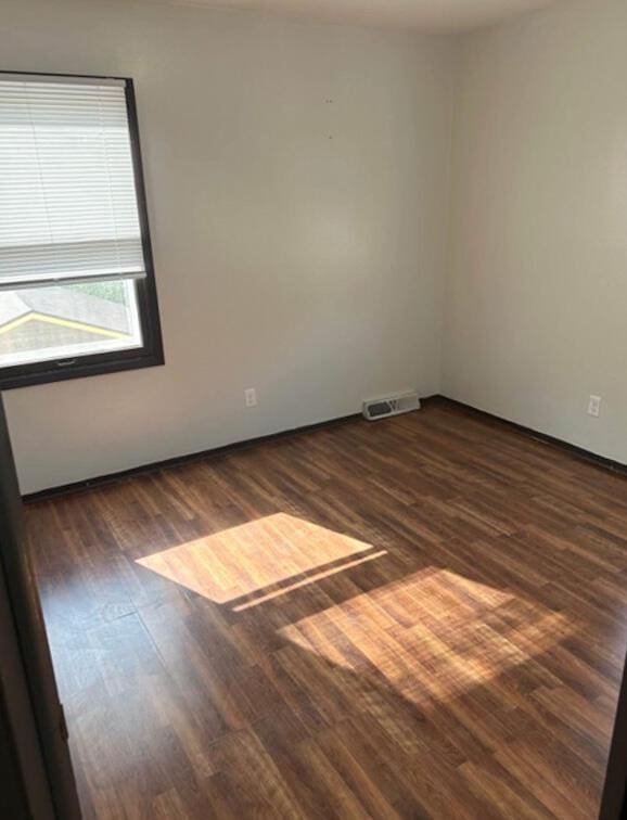 spare room with baseboards, wood finished floors, and visible vents