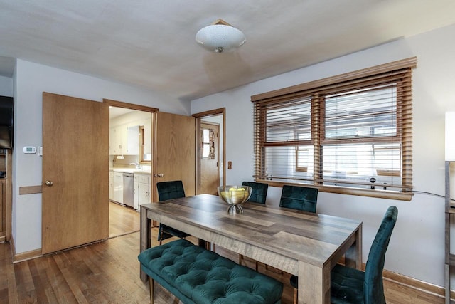 dining space with baseboards and light wood-type flooring