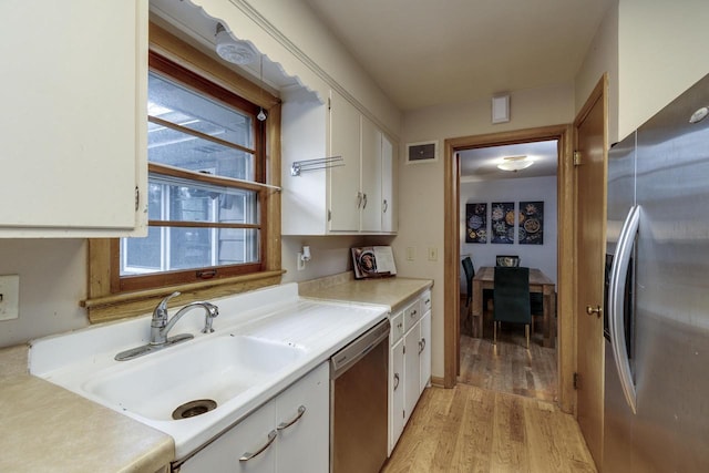 kitchen with a sink, stainless steel appliances, light wood-type flooring, visible vents, and white cabinets