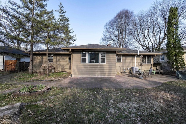 rear view of property with a patio, a chimney, and fence