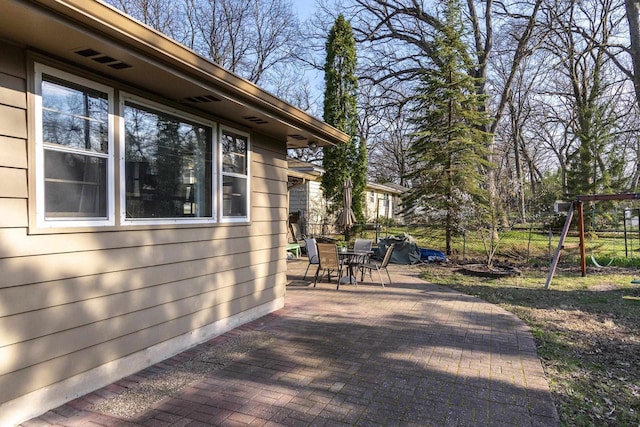 wooden deck with fence, outdoor dining area, a playground, and a patio area