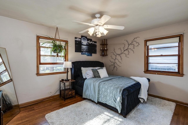 bedroom with wood finished floors, baseboards, and multiple windows