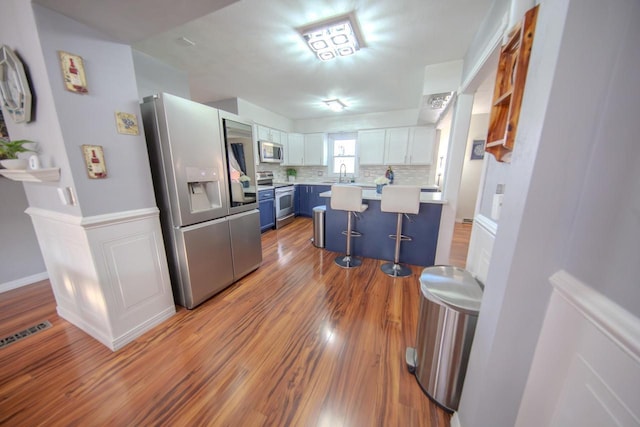 2607 King James Way, Fitchburg, WI 53719 - kitchen featuring a kitchen breakfast bar, stainless steel appliances, light countertops, a sink, and blue cabinetry