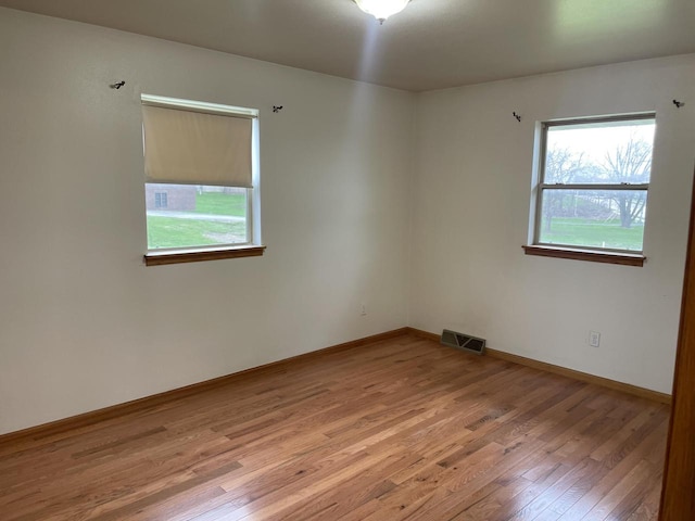 unfurnished room featuring light wood finished floors, baseboards, and visible vents