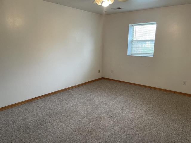 carpeted spare room with baseboards, a ceiling fan, and visible vents