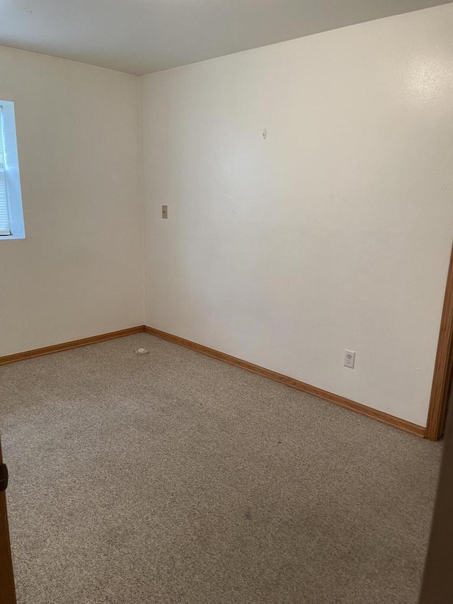spare room featuring baseboards and carpet