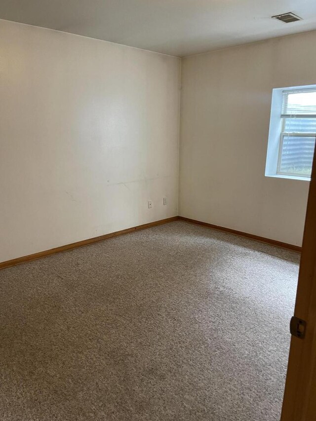 carpeted spare room featuring baseboards and visible vents